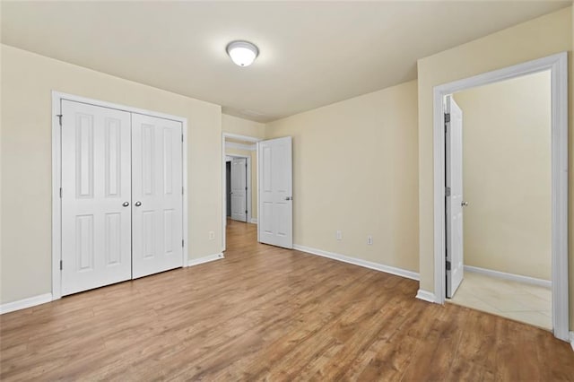 unfurnished bedroom featuring a closet, baseboards, and light wood finished floors