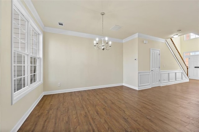 unfurnished room featuring an inviting chandelier, visible vents, ornamental molding, and wood finished floors