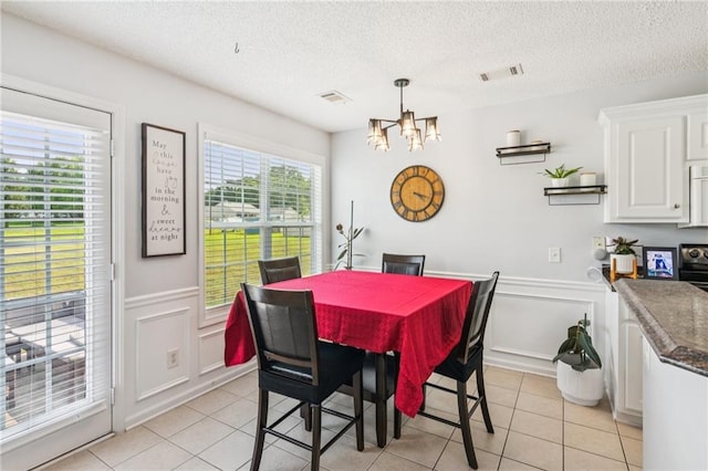 1671 Bismarck Cir, Winder, GA 30680 - dining area with a chandelier, wainscoting, light tile patterned floors, a decorative wall, and a textured ceiling