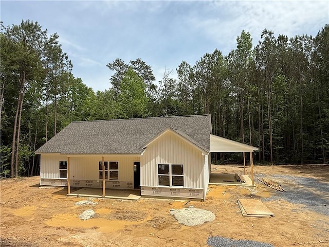 view of front of home with a shingled roof, board and batten siding, and a forest view