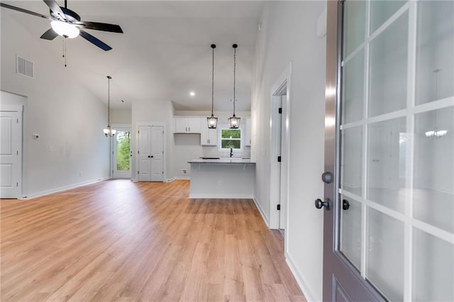 unfurnished living room featuring a ceiling fan, healthy amount of natural light, high vaulted ceiling, light wood finished floors, and baseboards