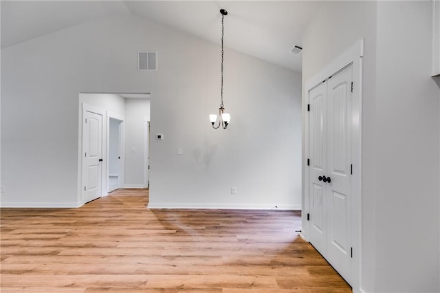 empty room with light wood-style flooring, high vaulted ceiling, baseboards, and a chandelier