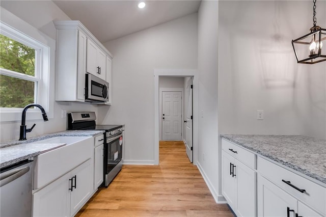 kitchen featuring appliances with stainless steel finishes, light wood-style flooring, white cabinetry, recessed lighting, and light stone counters