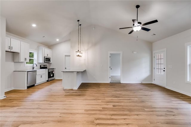 kitchen featuring appliances with stainless steel finishes, open floor plan, white cabinetry, light wood-type flooring, and high vaulted ceiling