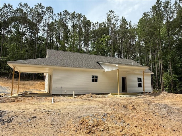 view of front of home featuring a shingled roof and dirt driveway