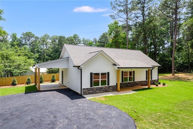 modern farmhouse with driveway, roof with shingles, stone siding, and a carport