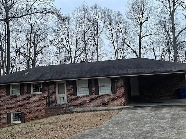 ranch-style house featuring crawl space, brick siding, driveway, and roof with shingles