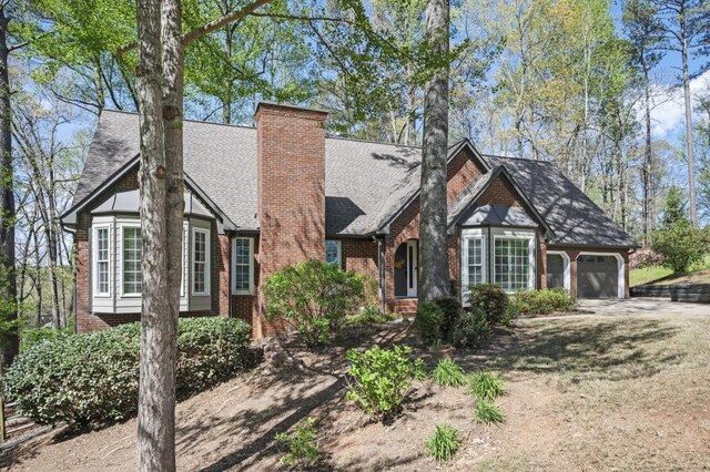 2689 Spring Rock Ct NE, Roswell, GA 30075 - tudor house featuring a garage, brick siding, a chimney, and roof with shingles