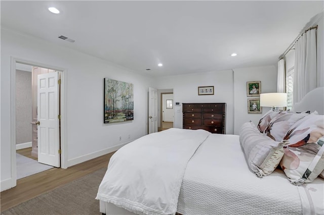 bedroom with ensuite bathroom and wood-type flooring