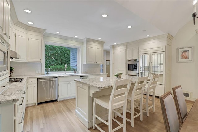 kitchen featuring dishwasher, tasteful backsplash, light stone countertops, light hardwood / wood-style floors, and a kitchen island