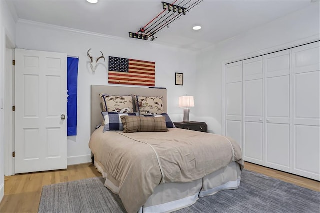 bedroom featuring crown molding, light hardwood / wood-style flooring, and a closet