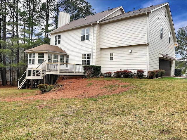 back of property with a deck, a yard, and a garage