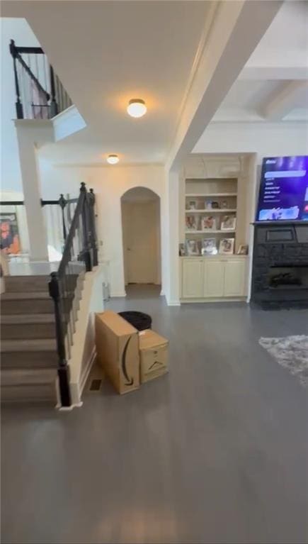 foyer entrance featuring stairway, arched walkways, beamed ceiling, and finished concrete floors