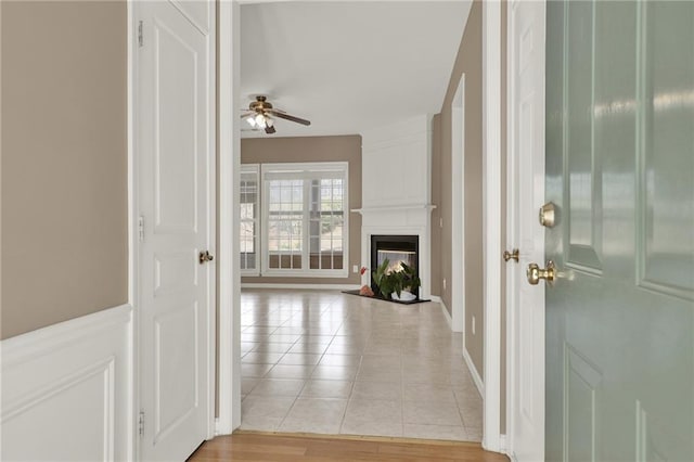 foyer with a large fireplace, ceiling fan, and light tile patterned flooring