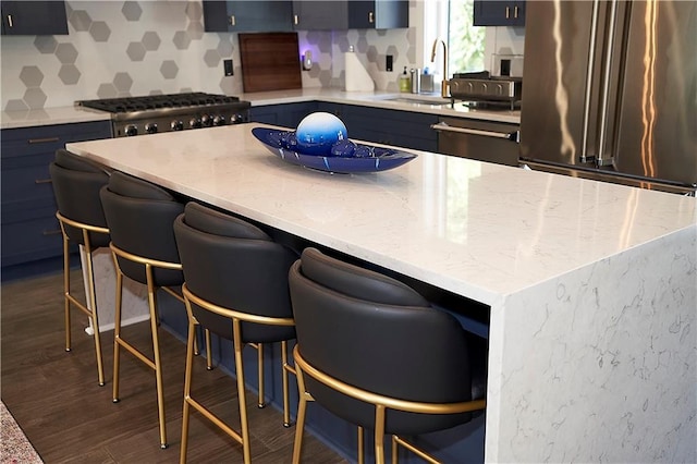 kitchen featuring stainless steel appliances, dark wood finished floors, blue cabinets, and a sink