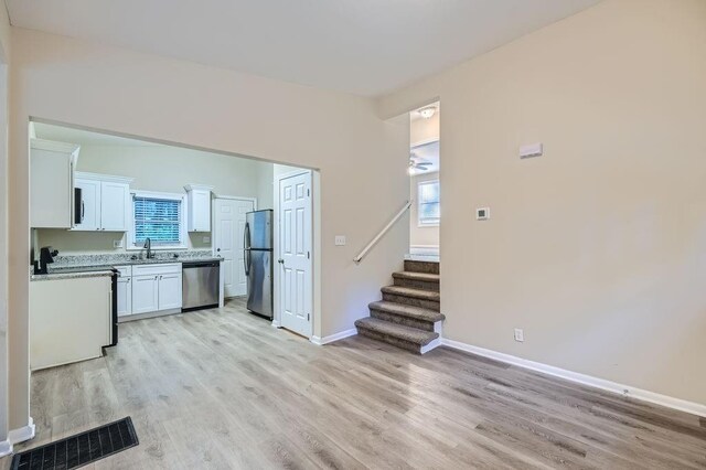 interior space with light hardwood / wood-style flooring, sink, stainless steel appliances, and white cabinets