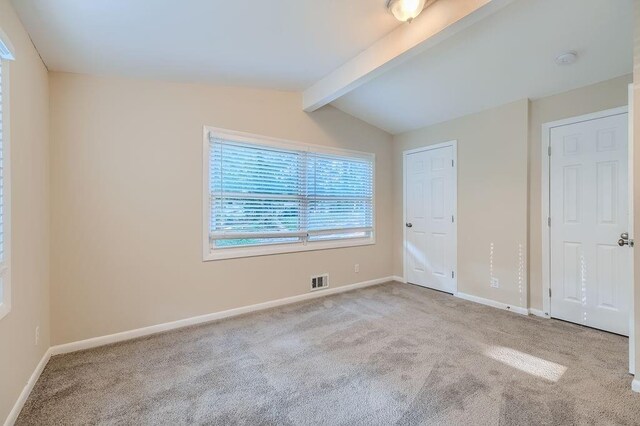 unfurnished bedroom with lofted ceiling with beams and carpet floors