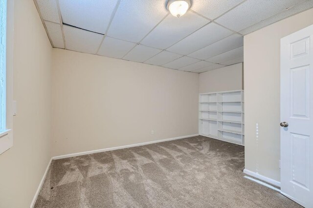 empty room with a paneled ceiling and carpet flooring