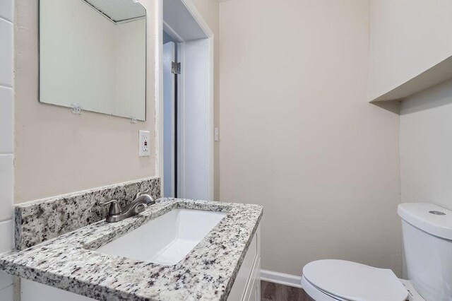 bathroom with vanity, toilet, and hardwood / wood-style floors