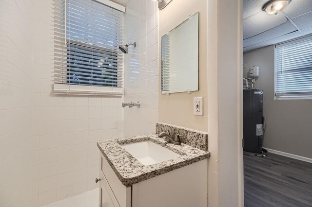 bathroom featuring hardwood / wood-style floors, water heater, a paneled ceiling, and vanity