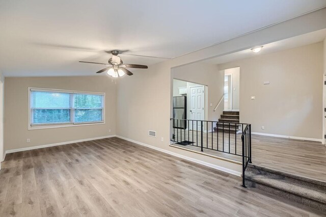 empty room with light wood-type flooring, vaulted ceiling, and ceiling fan