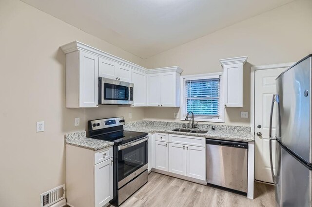 kitchen featuring light wood-type flooring, sink, appliances with stainless steel finishes, and white cabinetry