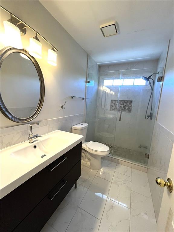 4770 Powers Park Ct NE, Marietta, GA 30067 - full bath featuring tile walls, marble finish floors, vanity, a shower stall, and toilet