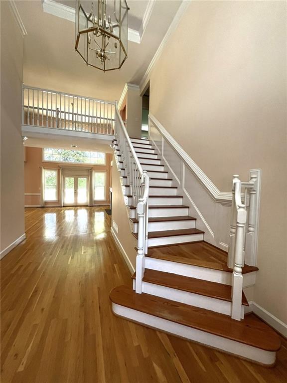 4770 Powers Park Ct NE, Marietta, GA 30067 - stairs featuring a high ceiling, wood finished floors, crown molding, a chandelier, and baseboards