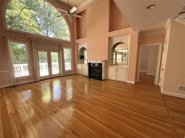 4770 Powers Park Ct NE, Marietta, GA 30067 - unfurnished living room with crown molding, ceiling fan, a towering ceiling, light wood-type flooring, and a fireplace with flush hearth