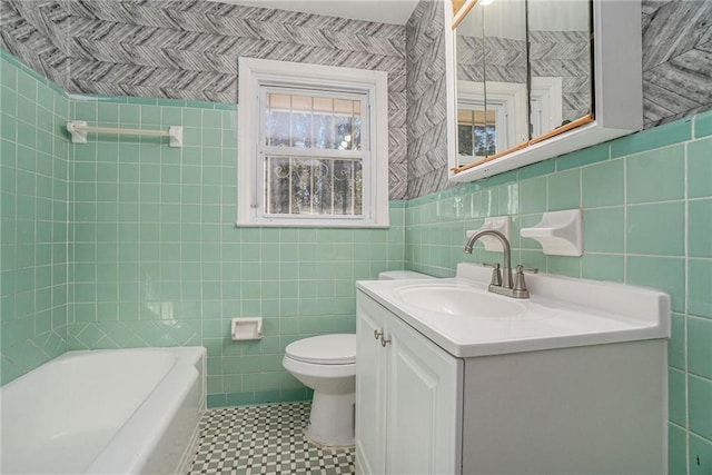 bathroom featuring tile walls, a bath, vanity, and toilet