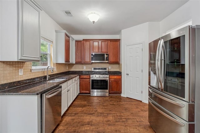 4515 Ambassador Way, Cumming, GA 30040 - kitchen featuring appliances with stainless steel finishes, a sink, backsplash, dark wood-style flooring, and dark stone countertops
