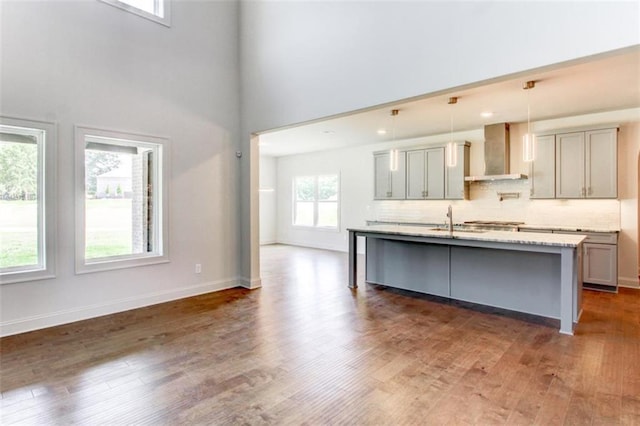 3065 Reserve Ct SW, Conyers, GA 30094 - kitchen featuring wall chimney exhaust hood, gray cabinets, dark wood-style flooring, a center island with sink, and tasteful backsplash