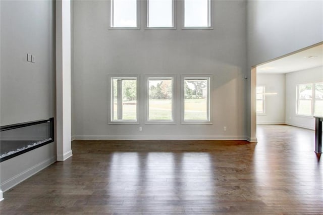 3065 Reserve Ct SW, Conyers, GA 30094 - unfurnished living room with wood finished floors, a high ceiling, baseboards, and a glass covered fireplace