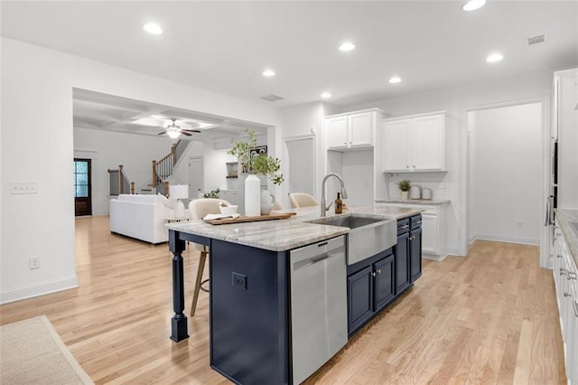 kitchen featuring sink, white cabinetry, dishwasher, light wood-type flooring, and an island with sink