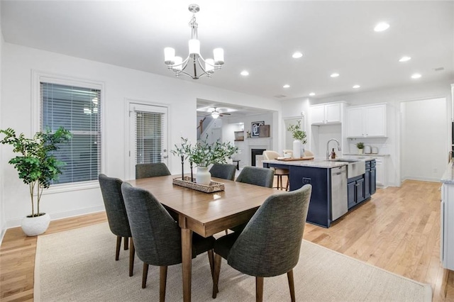 dining room featuring ceiling fan with notable chandelier, light hardwood / wood-style flooring, and sink