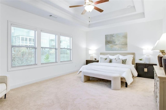 bedroom with ceiling fan, a tray ceiling, ornamental molding, and light colored carpet