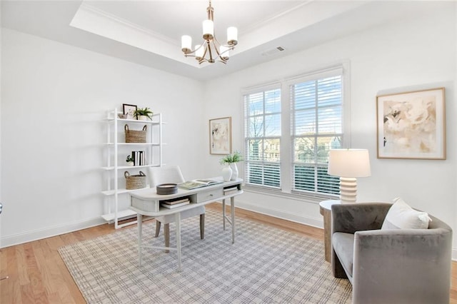 office area with hardwood / wood-style flooring, a tray ceiling, and a chandelier