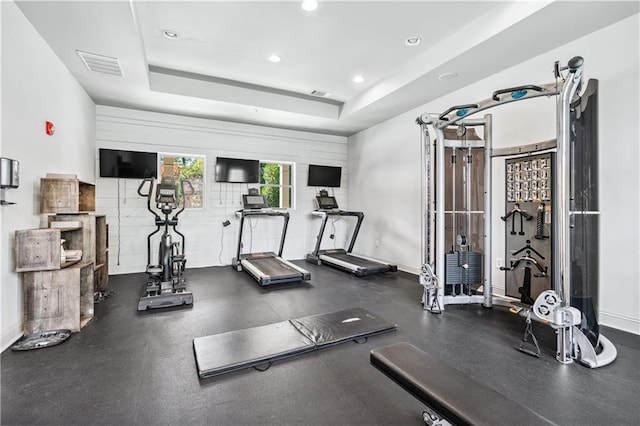 workout area with a tray ceiling