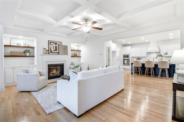 living room with coffered ceiling, built in shelves, and beam ceiling