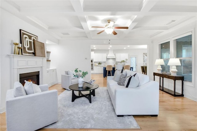 living room featuring light wood-type flooring, coffered ceiling, and beamed ceiling