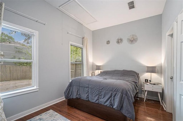 bedroom with attic access, dark wood-style flooring, visible vents, and baseboards