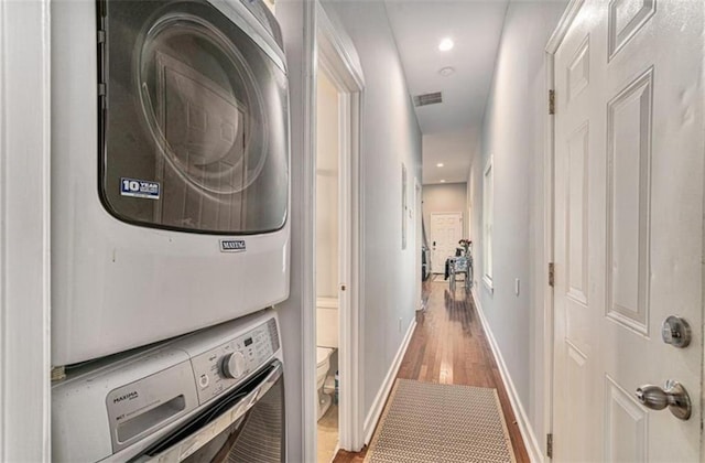 interior space with visible vents, baseboards, wood finished floors, stacked washing maching and dryer, and recessed lighting