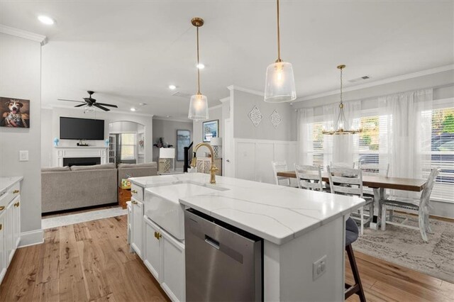 kitchen with dishwasher, hanging light fixtures, a kitchen island with sink, white cabinetry, and a sink