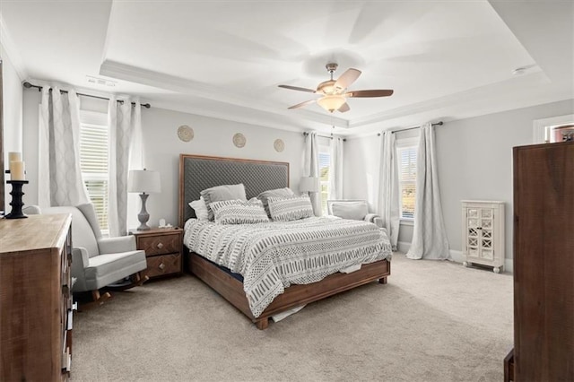 bedroom featuring baseboards, a tray ceiling, a ceiling fan, and light colored carpet