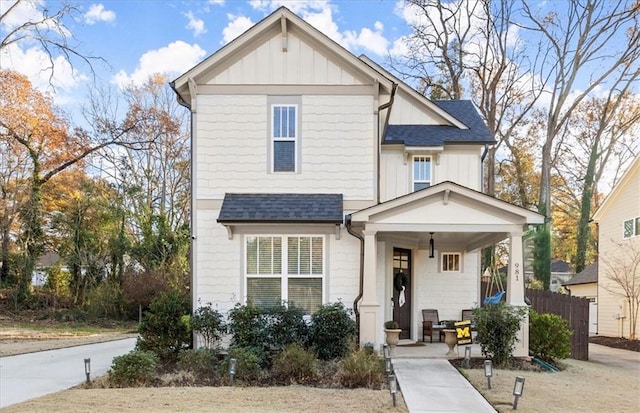 view of front of house featuring roof with shingles, board and batten siding, and fence