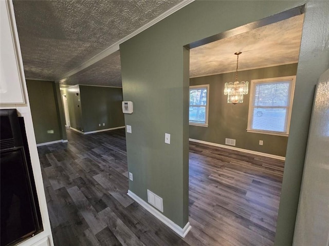 hall featuring crown molding, dark hardwood / wood-style floors, an inviting chandelier, and a textured ceiling