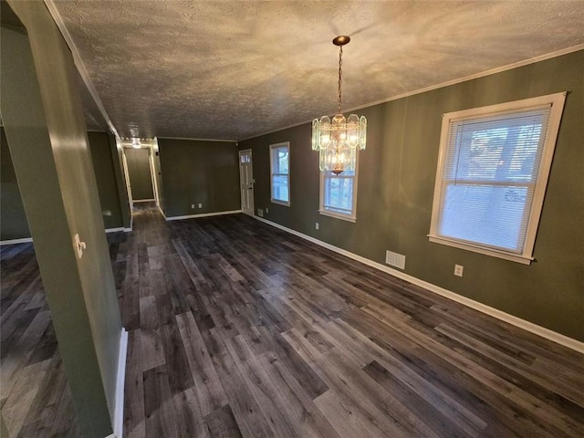 unfurnished dining area featuring crown molding, dark wood-type flooring, a notable chandelier, and a textured ceiling