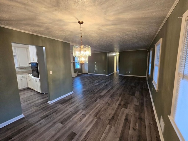 unfurnished dining area featuring dark wood-type flooring, ornamental molding, a textured ceiling, and a notable chandelier