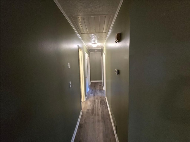 hallway featuring hardwood / wood-style flooring, ornamental molding, and a textured ceiling