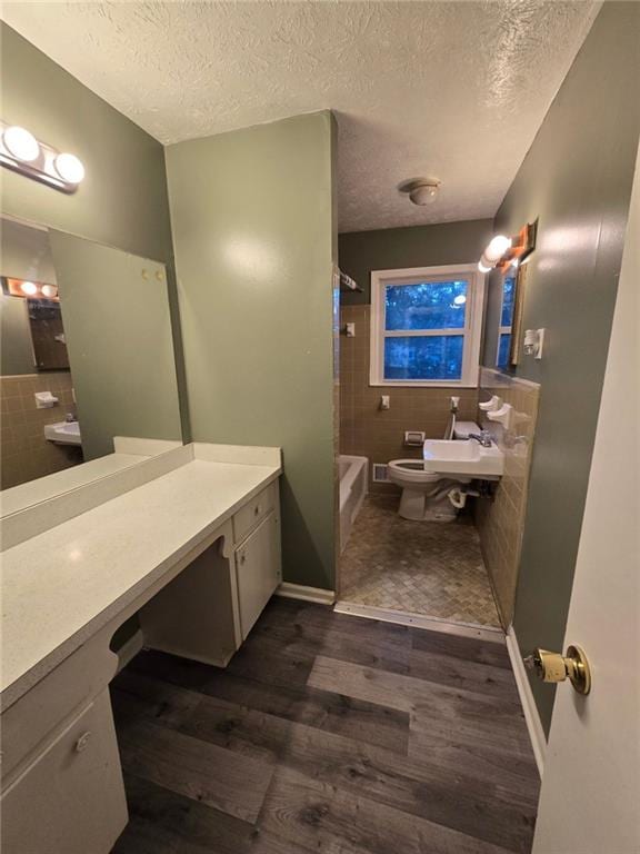 full bathroom with tiled shower / bath combo, wood-type flooring, a textured ceiling, and toilet